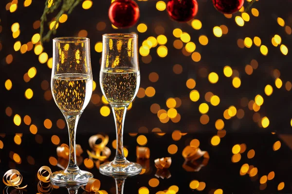 Dos copas de champán y bolas de Navidad sobre fondo de luces bokeh — Foto de Stock