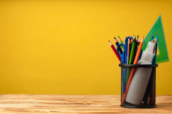 Schulbedarf auf Holztisch vor gelbem Hintergrund — Stockfoto