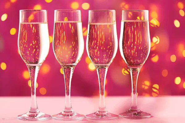 Quattro bicchieri di champagne sullo sfondo rosa con ghirlanda sfocata — Foto Stock