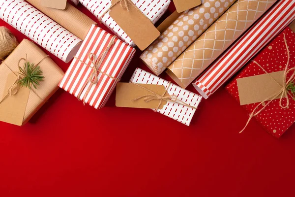 Kerstvoorbereidingen concept met inpakpapier, geschenkdozen op rode achtergrond — Stockfoto