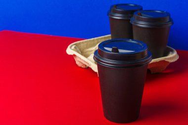 Koyu kahve fincanlarını kabın içinde götürür.