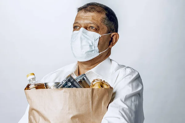 Hombre en una máscara médica protectora con una bolsa de una tienda de comestibles —  Fotos de Stock