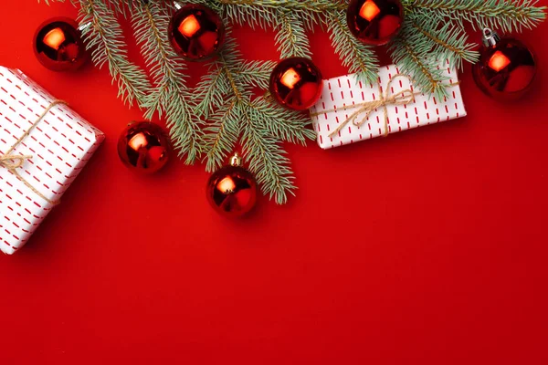 Різдвяний фон з ялинковими гілками та кульками на червоному — стокове фото