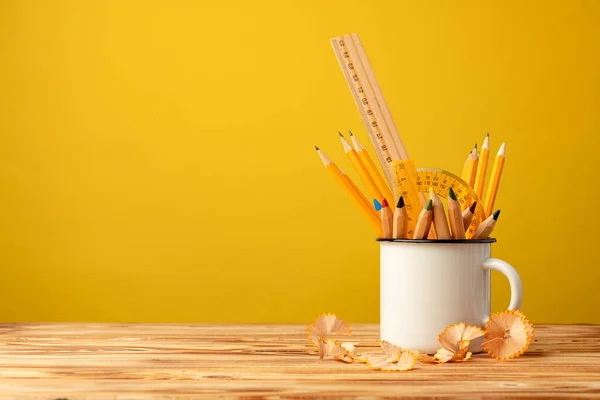 Металлическая чашка с острыми карандашами и стружками для карандашей на деревянном столе — стоковое фото