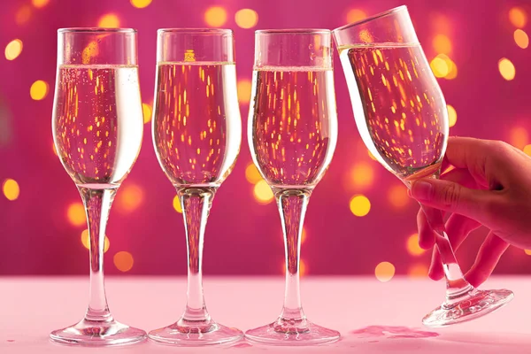 Pembe arka planda dört şampanya bardağı ve bulanık çelenk.