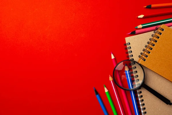 Kleurrijke potloden en notitieblokken op papieren achtergrond bovenaanzicht — Stockfoto