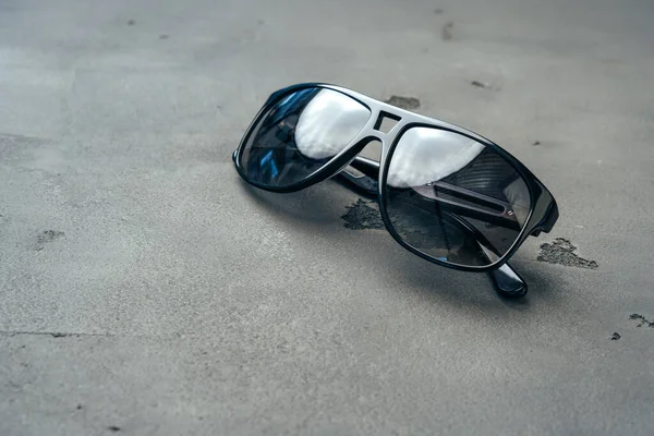 Dark male sunglasses on grey concrete surface — Stock Photo, Image