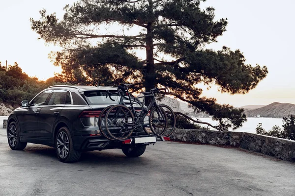 Askıya yüklenmiş iki yol bisikletiyle kesişen araba.