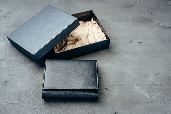 Black leather wallet on grey concrete background