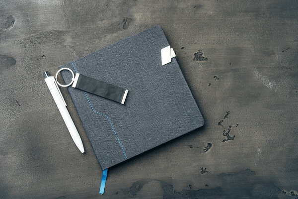 Male accessories notepad and pen on dark grunge surface