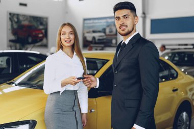 Genç ve çekici bir kadın araba galerisinden yeni bir araba alıyor.