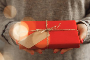 Süveter giymiş kadın elleri, paketlenmiş Noel hediyeleri.