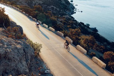 Bisikletli, sahil yolunda bisiklete biniyor.