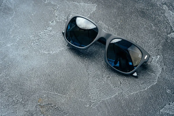 Dark male sunglasses on grey concrete surface — Stock Photo, Image