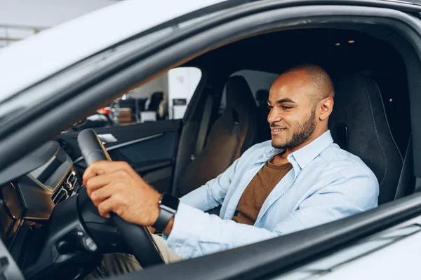 Portrait d'un bel homme afro-américain heureux assis dans sa voiture nouvellement achetée — Photo