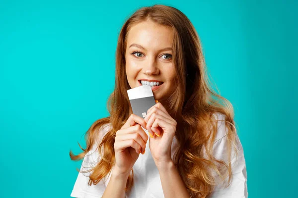 Sorridente giovane donna mordere una carta di credito nella tentazione di shopping — Foto Stock