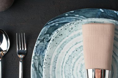 Masa ayarı. Siyah tabloda soyut desenli plakalar