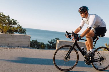 Kıyı yolunda bisiklet süren sporcu.