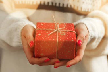 Süveter giymiş kadın elleri, paketlenmiş Noel hediyeleri.