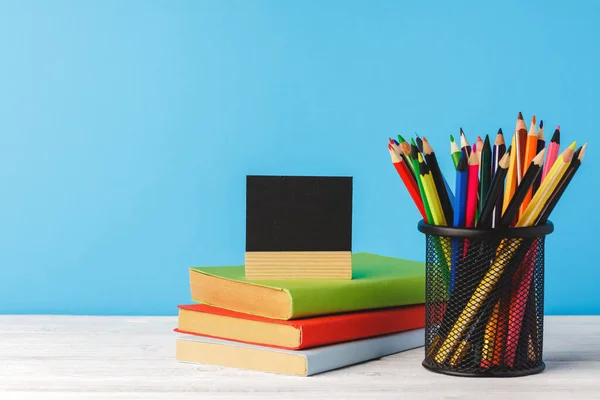 Beker van kleurpotloden en stapel boeken — Stockfoto