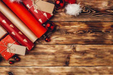 Kahverengi ahşap tahtada Noel hediyeleri için kağıt rulo paketleme