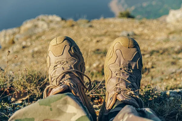 Man traveler in hiking boots sits on top — Stock Photo, Image