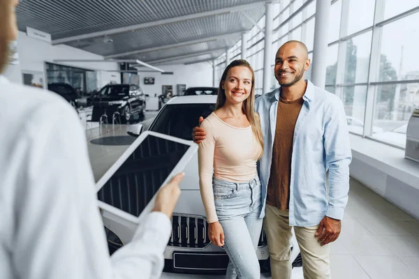 Vendedora de carros em uma concessionária de carros conversando com clientes — Fotografia de Stock