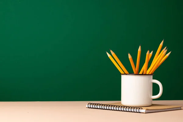 Forniture scolastiche su scrivania in legno contro lavagna verde — Foto Stock