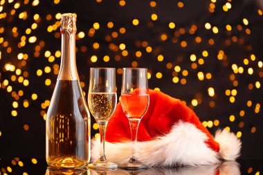 Şampanya ve Noel Baba şapkası bulanık çelenk arka planında