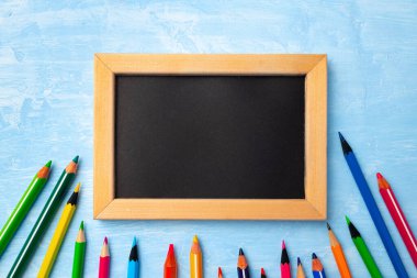 Etrafı renkli kalemlerle çevrili ahşap çerçeveli küçük tahtalar.