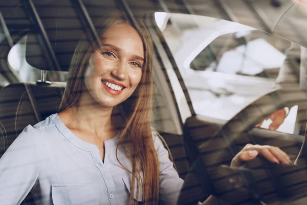 Attraktive junge Frau sitzt in Neuwagen im Showroom — Stockfoto