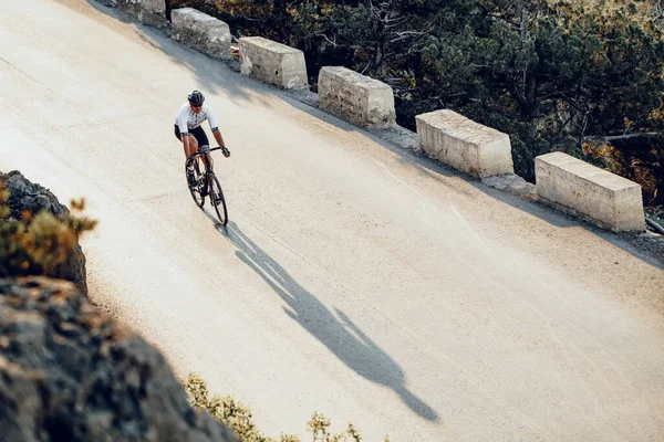 Ciclista professionista su una strada di montagna all'alba — Foto Stock