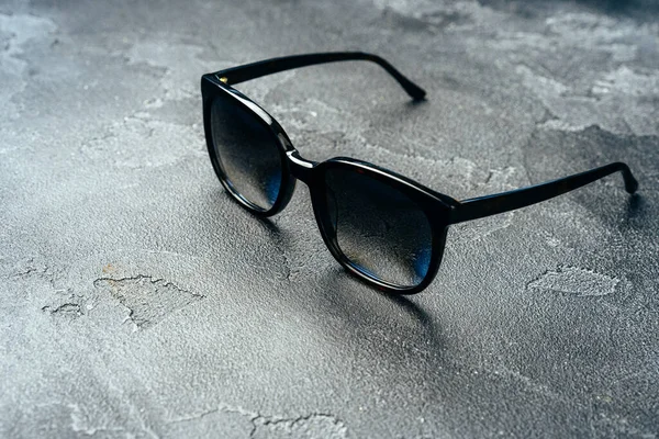 Dark male sunglasses on grey concrete surface — Stock Photo, Image