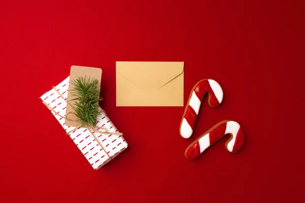 Vánoční dárek a perník sušenky na červeném pozadí — Stock fotografie