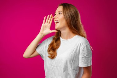 Genç bir kadın elini tüp gibi kullanarak bağırıyor.