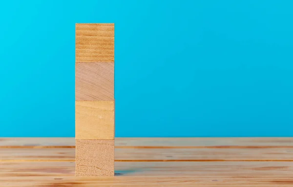 Blocos de madeira empilhados na mesa de madeira contra fundo azul — Fotografia de Stock
