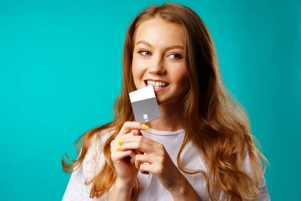 Sorridente giovane donna mordere una carta di credito nella tentazione di shopping — Foto Stock