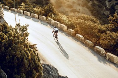 Bisikletli, sahil yolunda bisiklete biniyor.