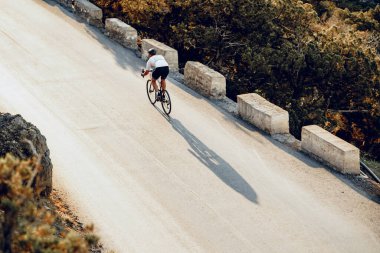 Bisikletli, sahil yolunda bisiklete biniyor.