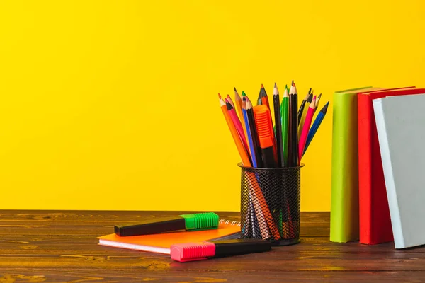 Beker van kleurpotloden en stapel boeken — Stockfoto