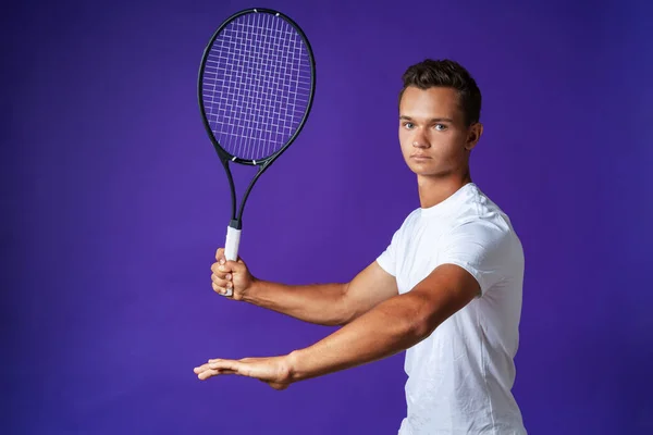 Jovem jogador de tênis branco posando com raquete de tênis contra fundo roxo — Fotografia de Stock