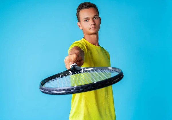 Jovem jogador de tênis em sportswear posando contra fundo azul — Fotografia de Stock