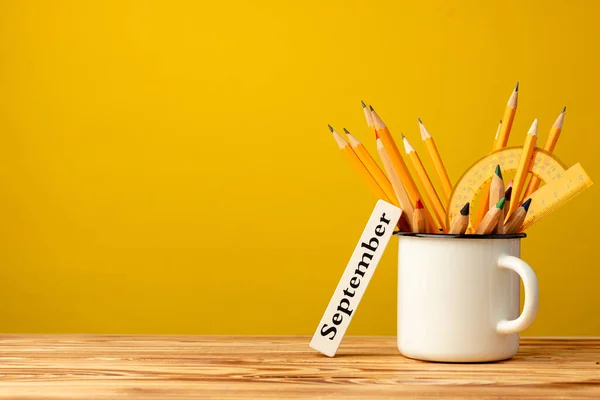 Copo de escritório com lápis e artigos de papelaria contra fundo amarelo — Fotografia de Stock