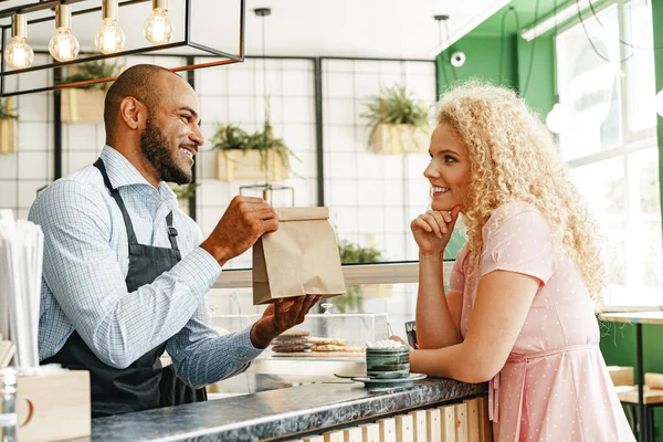 カウンターでコーヒーショップのウエイターと話しているブロンドの女性の笑顔 — ストック写真