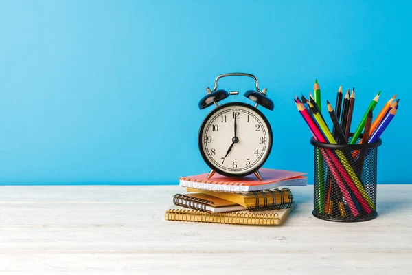 Schulbedarf auf Holztisch vor blauem Hintergrund — Stockfoto
