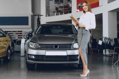 Galeride genç ve güzel bir kadın araba satıcısı var.
