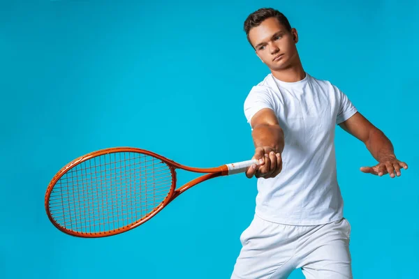 Jeune homme joueur de tennis en vêtements de sport posant sur fond bleu — Photo