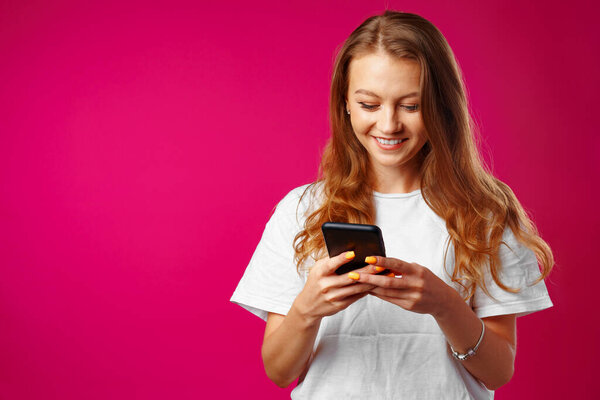Young smiling woman standing and using her smartphone
