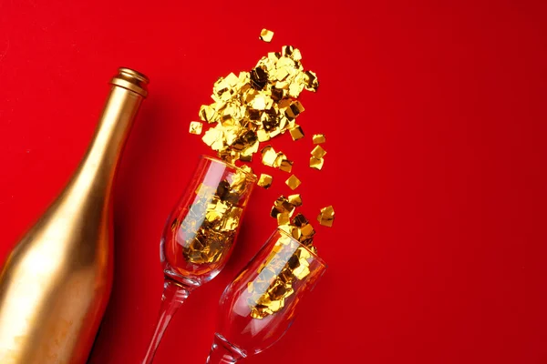 Champagne glas met glitter confetti op rode achtergrond plat gelegd — Stockfoto