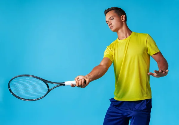 Young man tennis player in sportswear posing against blue background